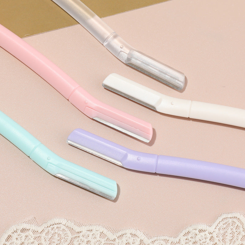 Close up of the angled blade heads of five eyebrow razors in pink, white, mint green, purple and frosted transparent