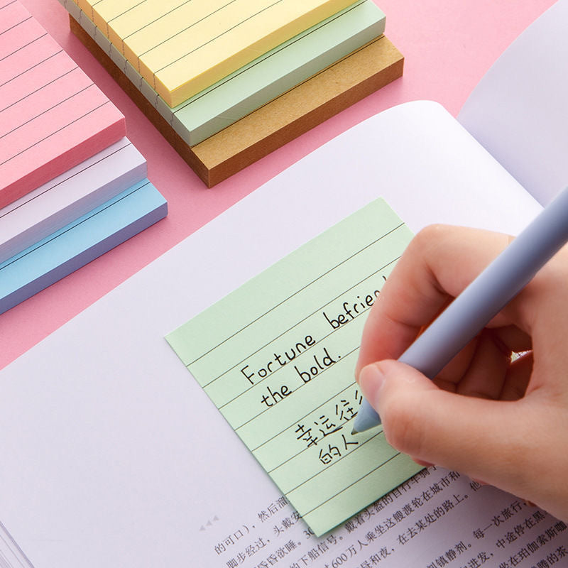 Blue lined sticky note stuck to a lined notebook page with handwriting across the ruling