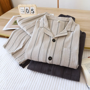 Folded light gray and dark gray striped pajama sets on a bed with a desk calendar and a book
