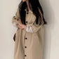 Light khaki long single breasted trench coat with lapel collar and buttoned front on a model