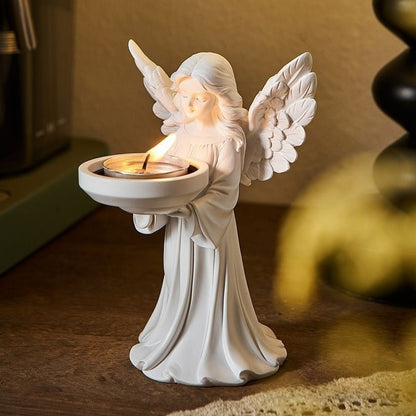White matte angel figure holding a dish with a tea light, front view on a wood table