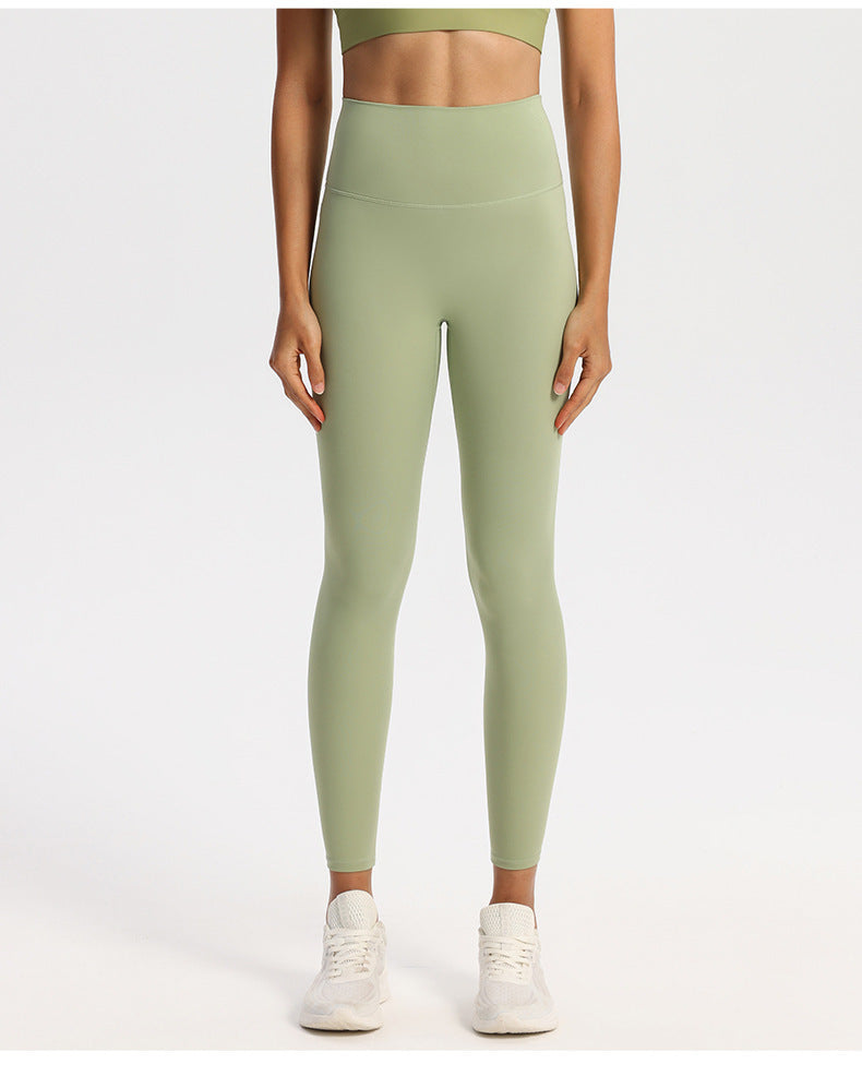 Wide high-rise waistband yoga leggings, nylon spandex knit, worn against a studio wall