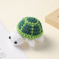 Crocheted dark green and light green shell white turtle, handmade wool charm on a cream surface