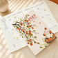 Monthly planner notebook shown open with a monthly grid and lined pages