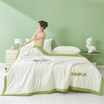 White seersucker summer quilt with an emerald green border on a styled bed by a green wall