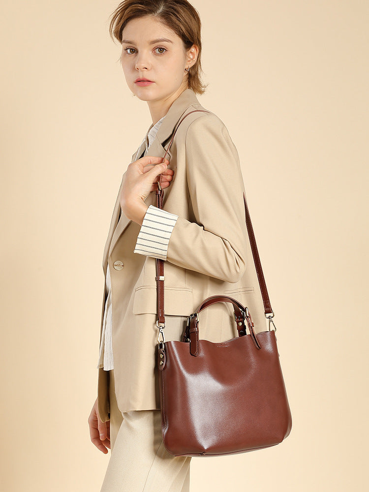 Woman carrying the chestnut brown leather bucket tote on the shoulder, side view