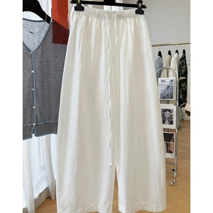 White wide leg pants with elastic drawstring waist hanging in a bright boutique