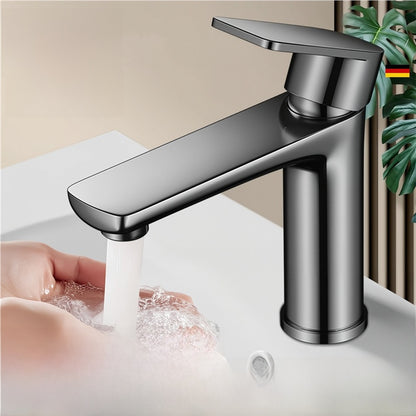 Gunmetal gray single lever bathroom faucet with a flat topped spout and water running over a hand above a white basin
