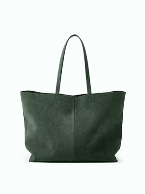 Dark green sandblasted leather tote bag standing upright with a center seam and arched straps on a light background