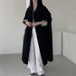 Black long trench coat with lapel collar and full button front worn over white trousers