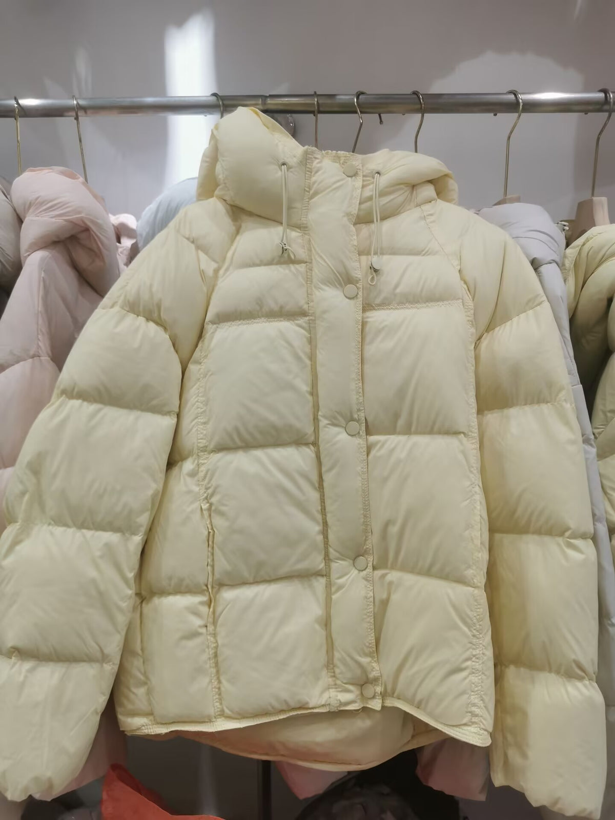 Down puffer jacket displayed flat, boxy loose cut with long rounded sleeves
