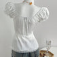 Back view of the white blouse on a dress form, plain gathered back, waist seam and scalloped lace hem