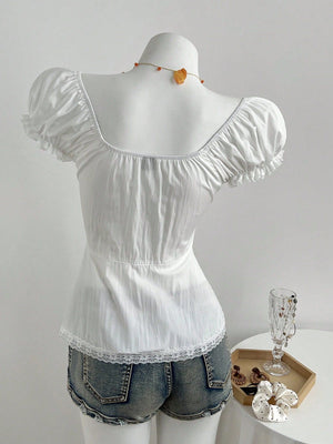 Back view of the white blouse on a dress form, plain gathered back, waist seam and scalloped lace hem