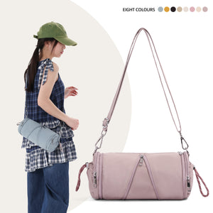 Woman in a green cap carrying a lilac nylon cylindrical shoulder bag by its long strap, with a small blue bag at her hip