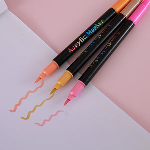 Three acrylic markers with soft brush tips drawing wavy strokes on white paper