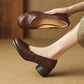 Brown embossed leather round block heel slip-on shoe worn on a foot, the other held to show the insole