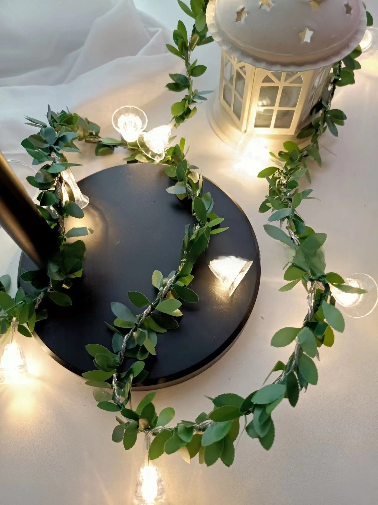 Bell LED fairy string light on a green leaf vine with a warm glow, decorative photo