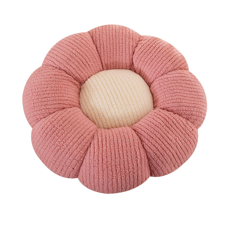 Flower shaped plush cushion held up to show its rounded knit petals and soft loft