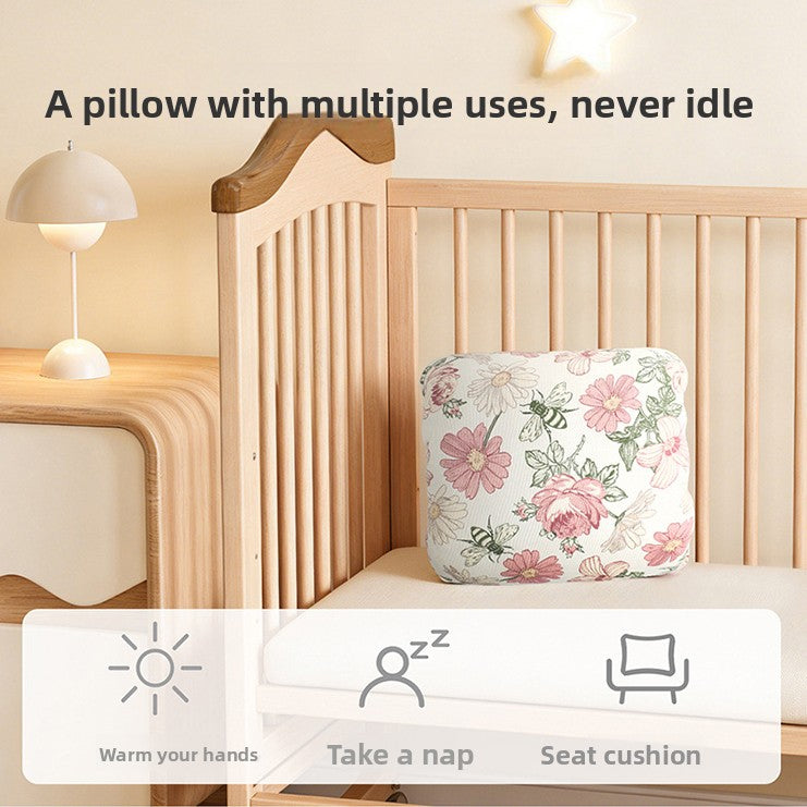 Hand resting on the nursing pillow to show its size and soft cushioned thickness