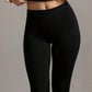 Black high-waisted leggings with a wide waistband, model lifting her top, front view