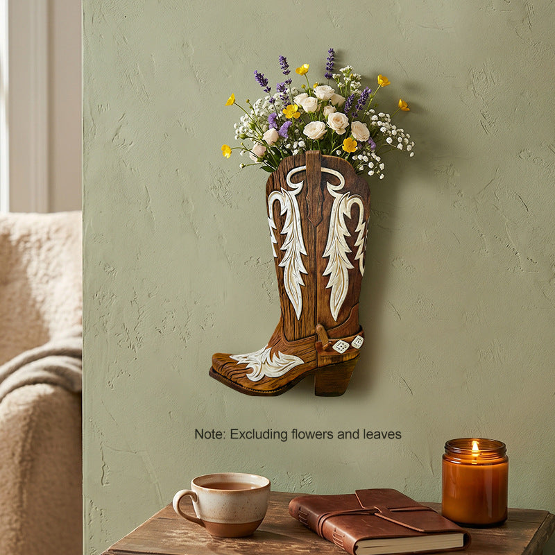 Wooden cowboy boot wall vase on a green wall with wildflowers in the top opening