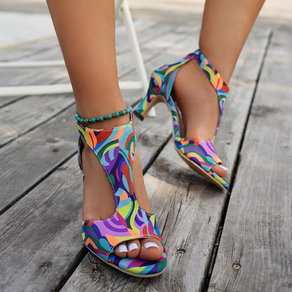 Woman wearing multicolor print T-strap peep toe sandals with a turquoise anklet on a wooden deck