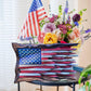 Wooden American flag wall art on a side table beside a bouquet of flowers