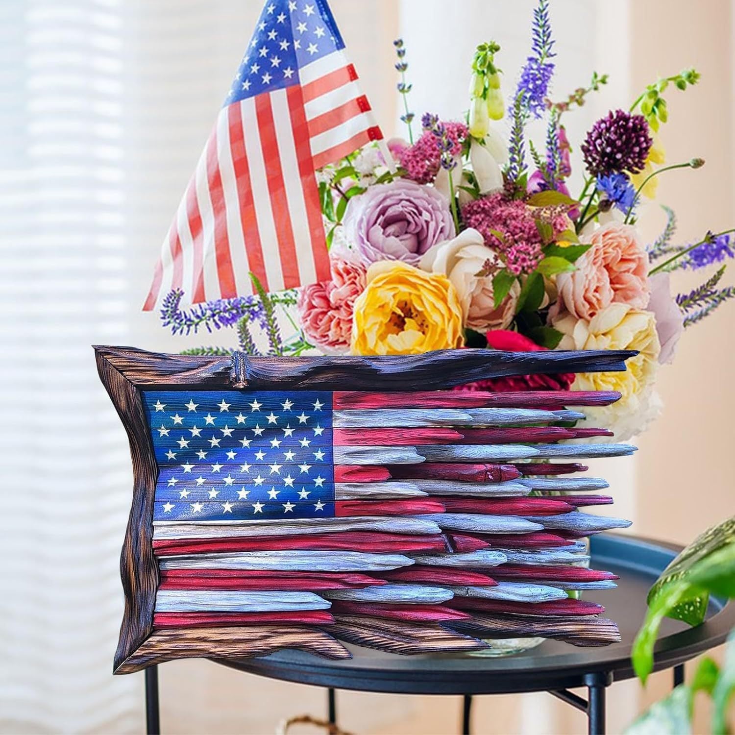 Wooden American flag wall art on a side table beside a bouquet of flowers