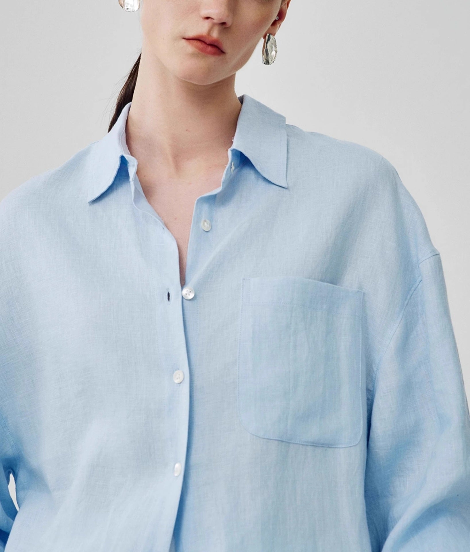 White relaxed linen shirt styled with a woven bag for a summer look