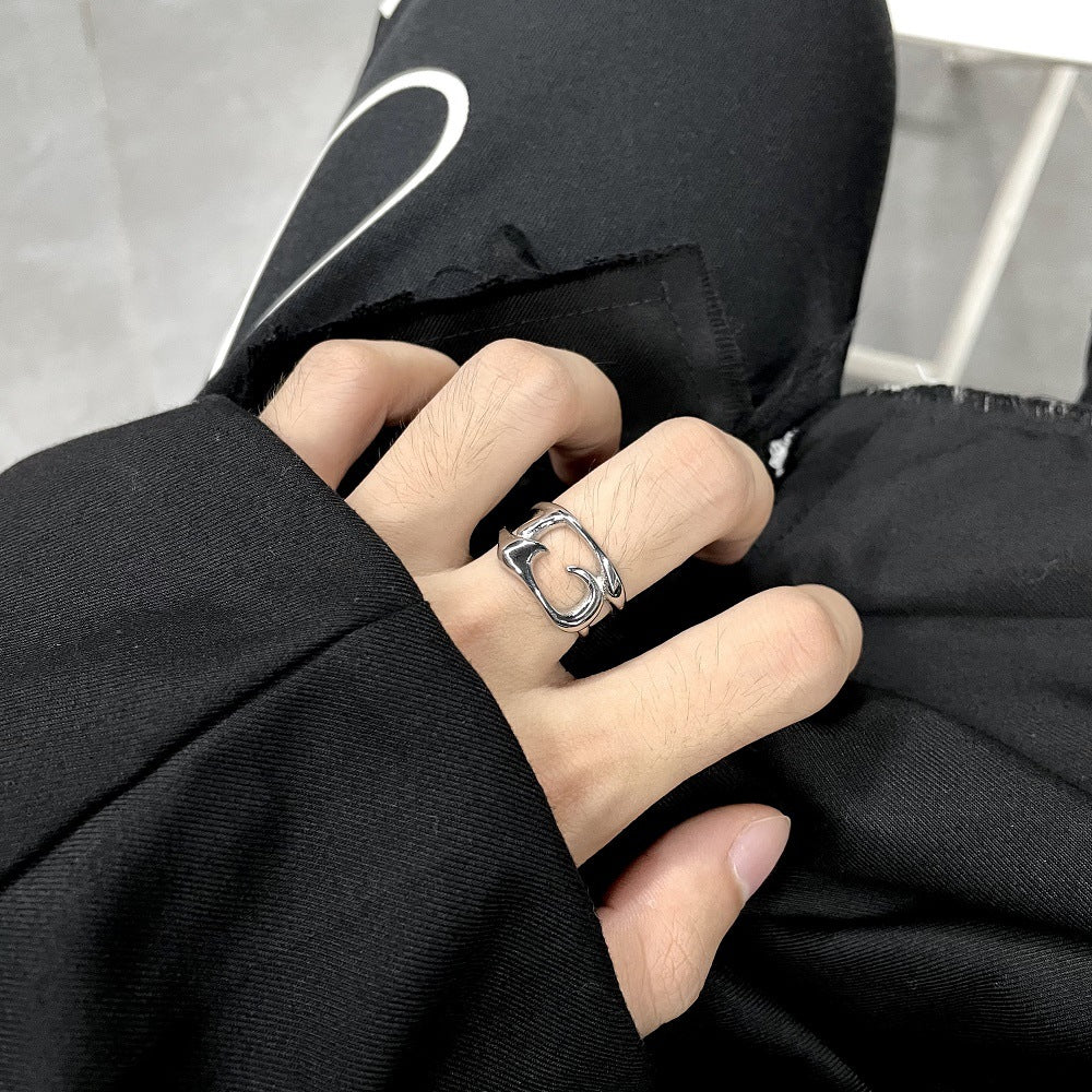 Silver tone openwork steel ring worn on a middle finger against a black sleeve