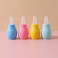 Row of pastel squeeze bulb baby nasal aspirators with clear caps removed beside the soft tips