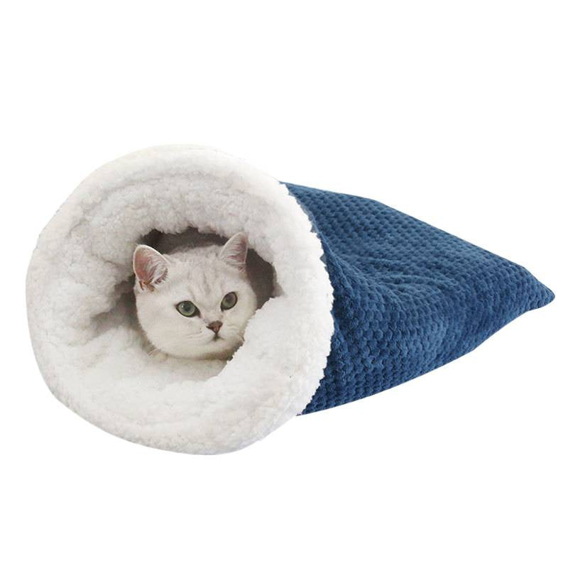 Dark blue waffle weave cat sleeping bag with white fleece lining on a white background, cat peeking out