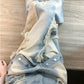 Washed blue wide leg baggy jeans with raw frayed appliques worn by a woman, streetwear styling