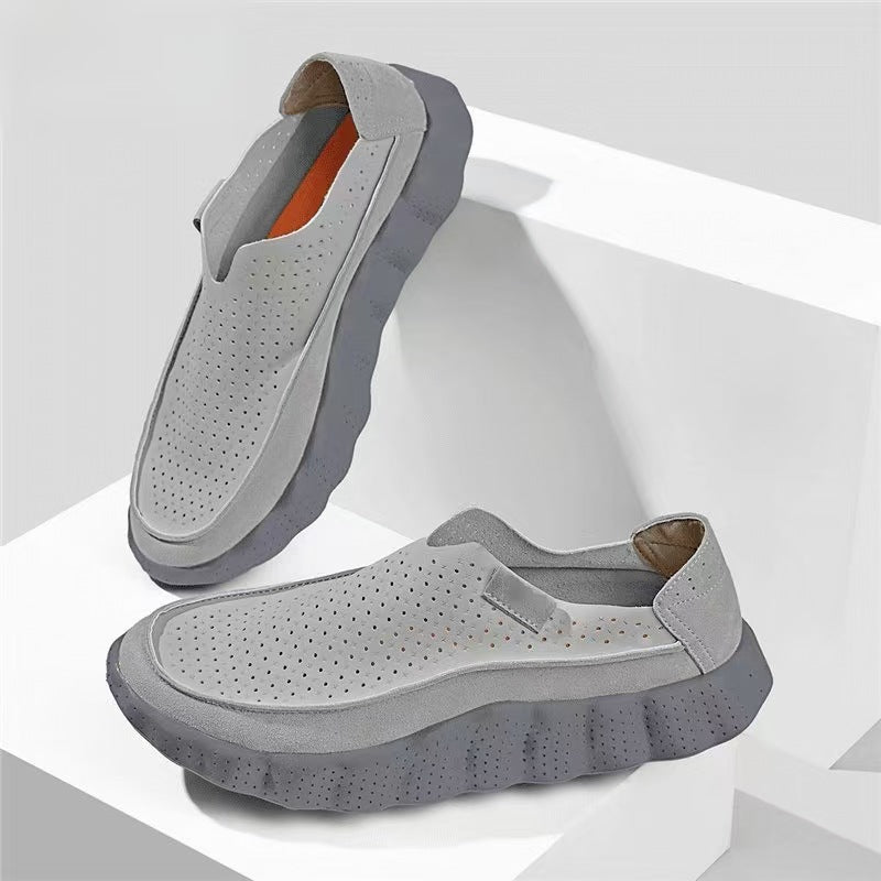 Light gray perforated slip-on loafers with a slate gray scalloped sole and an orange insole on a white stepped set