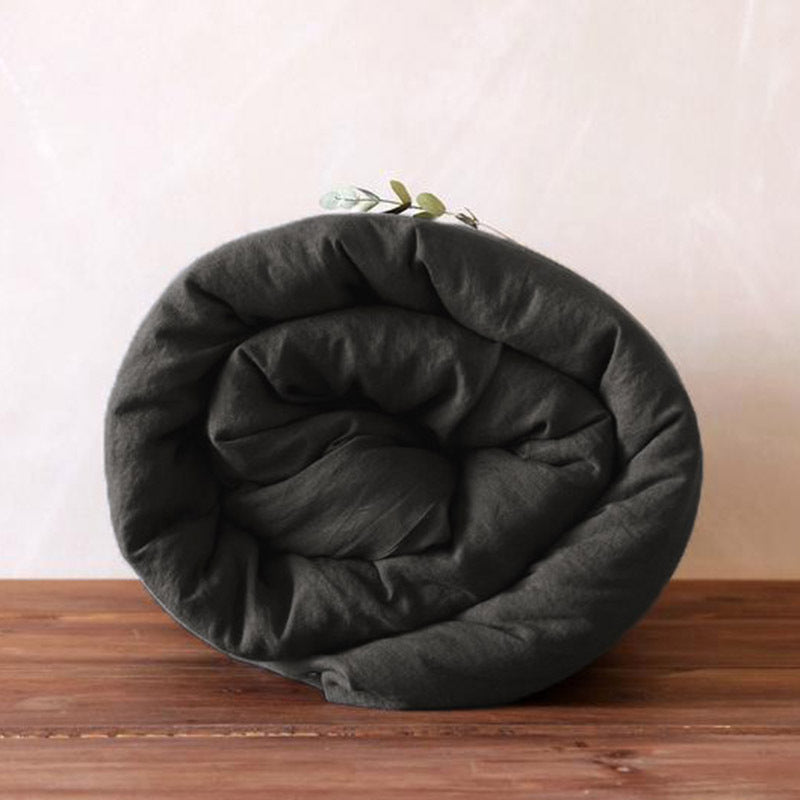 Washed pure linen duvet cover folded and rolled on a wooden surface