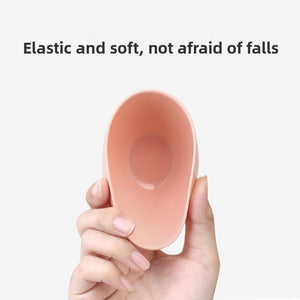 Pink flexible face mask mixing bowl held in hand with a spatula and powder scoop