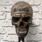 Resin skull helmet rack mounted on a wall holding a motorcycle helmet between rides