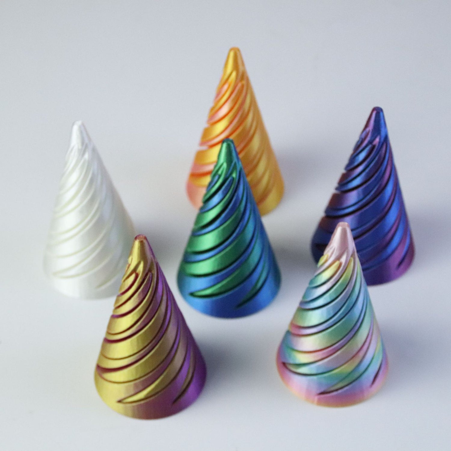 Six 3D printed spiral cones showing gradient filament and identical helical cuts on grey