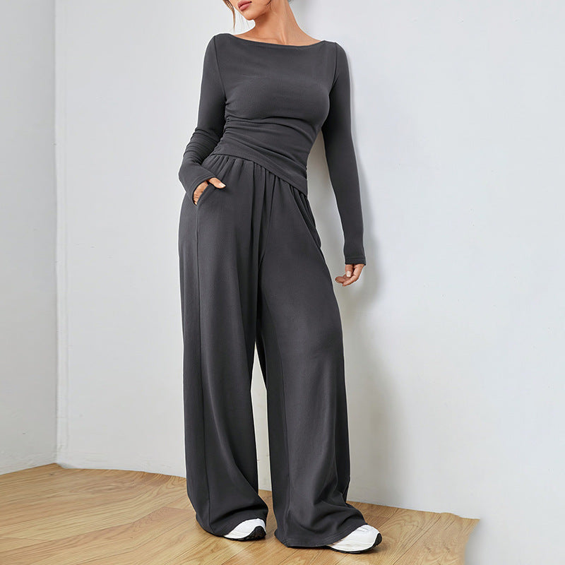 Dark gray fitted long sleeve top and wide leg pants set, standing with a hand in the side pocket