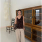 Khaki high waist wide leg trousers styled with a camisole beside wooden cabinet