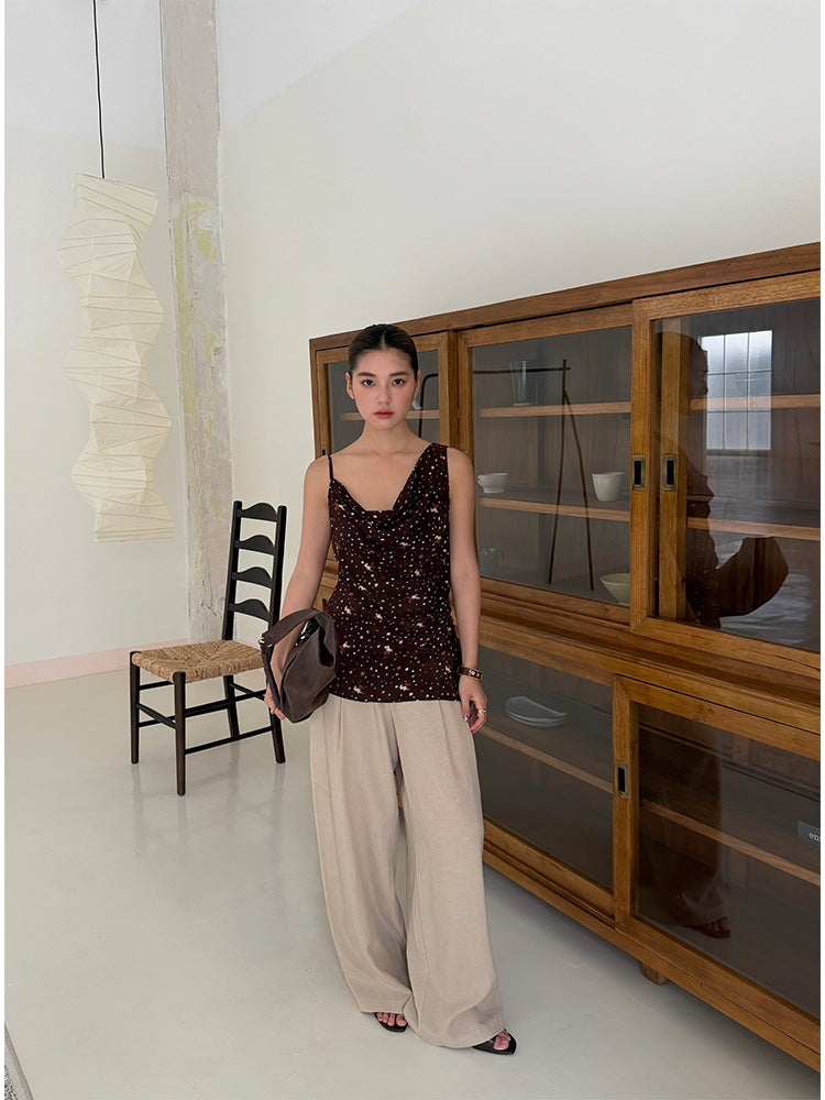 Khaki high waist wide leg trousers styled with a camisole beside wooden cabinet