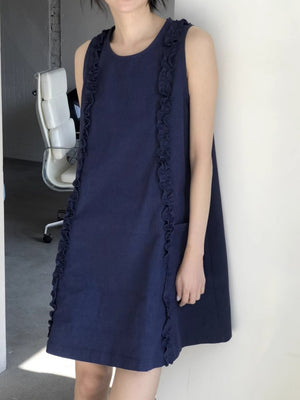 Navy blue loose A-line ruffle trim dress worn sleeveless, front three-quarter view