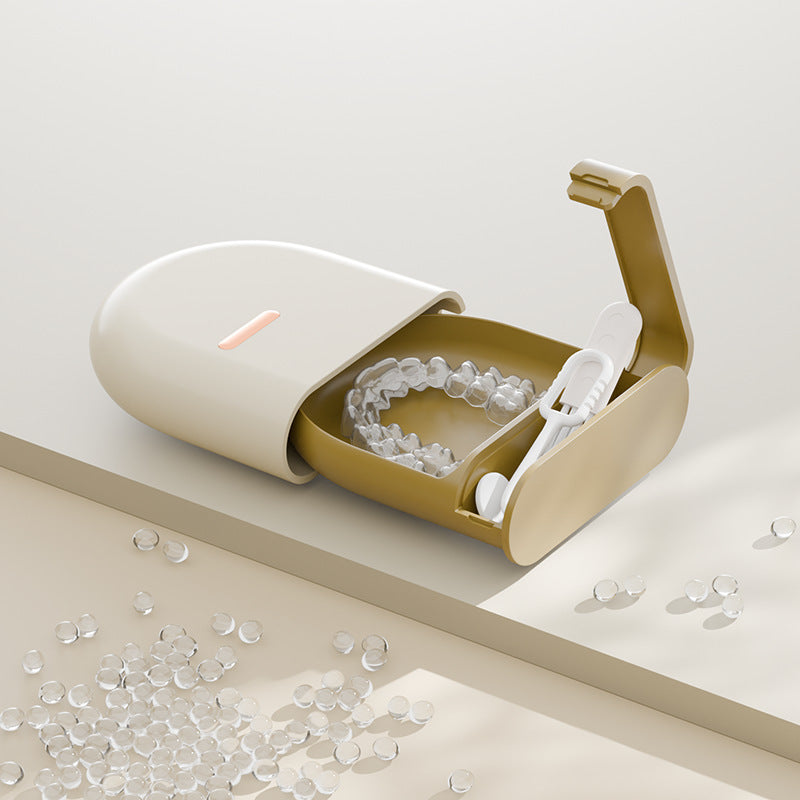 Open cream retainer storage case holding a clear retainer with a small tweezers inside
