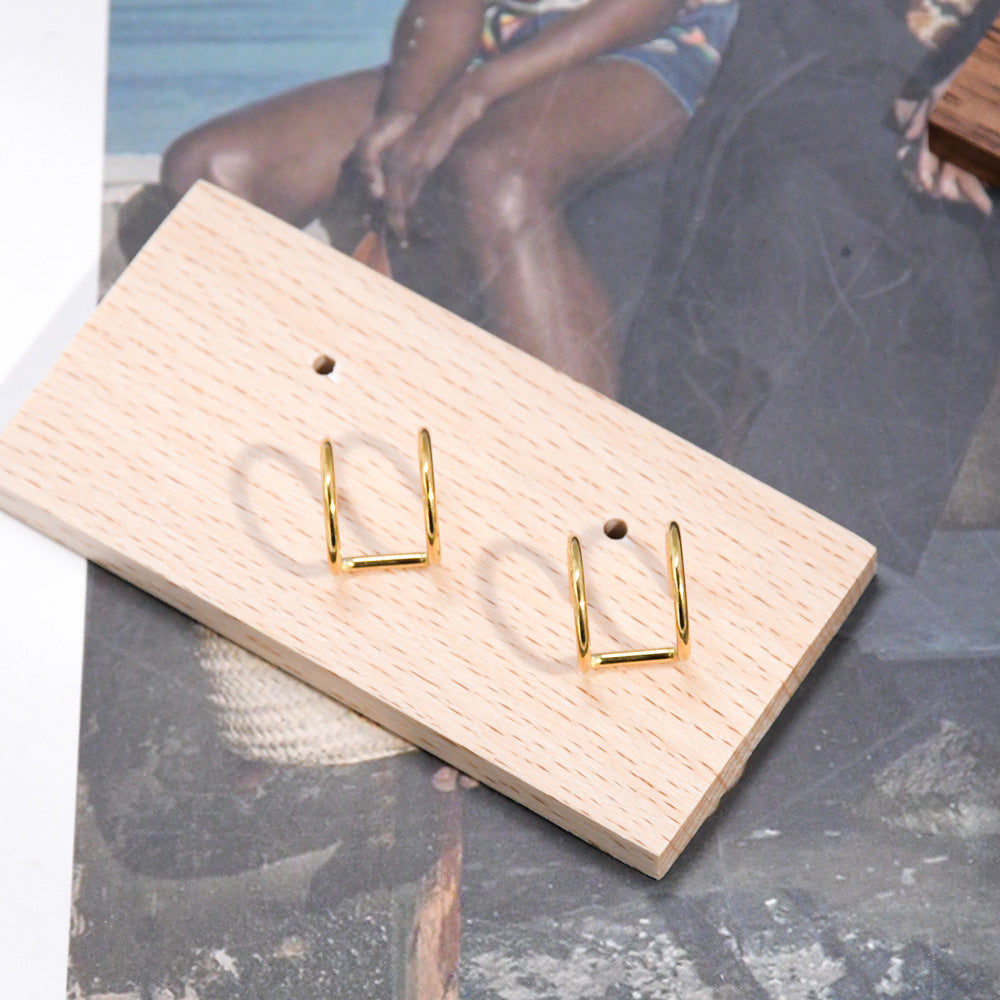 Pair of gold U shaped non pierced ear cuffs on a wood display block