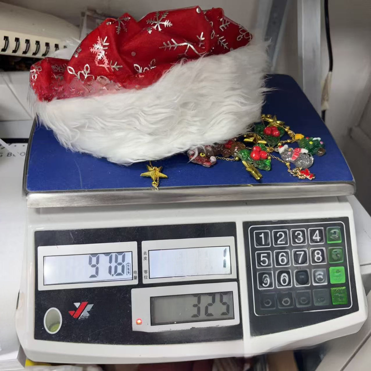 Red snowflake fabric hat with a plush white brim and loose charms weighed on a scale