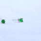 Side view of two green cabochon studs showing the straight posts and friction push backs on a hand