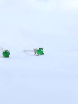 Side view of two green cabochon studs showing the straight posts and friction push backs on a hand