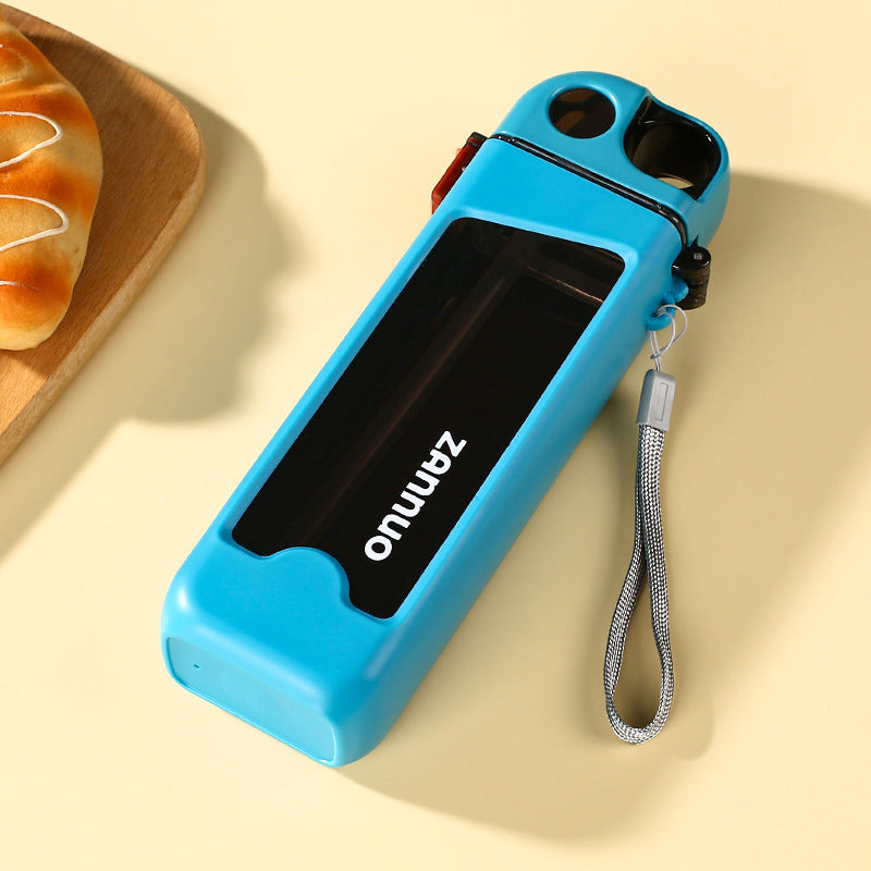 Teal square plastic sports water bottle lying flat with grey woven carrying strap on beige