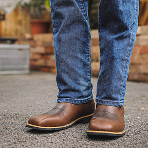 Mens brown western boots front view on pavement showing squared toe and welt