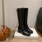 Pair of black leather knee high boots on a display block showing the smooth shaft and heel
